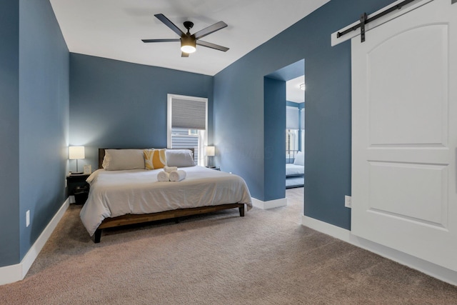 bedroom featuring a barn door, ceiling fan, and carpet floors