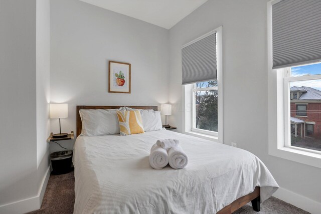 bedroom with multiple windows and dark colored carpet