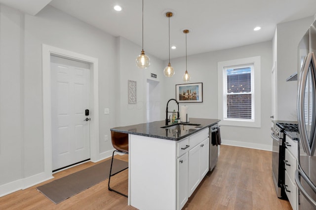 kitchen featuring pendant lighting, white cabinets, sink, an island with sink, and appliances with stainless steel finishes