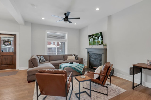 living room with a brick fireplace, light hardwood / wood-style flooring, and ceiling fan