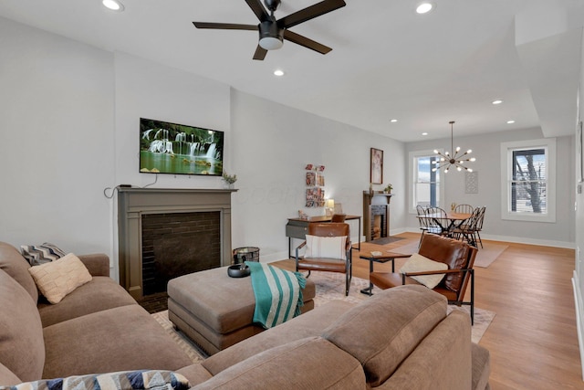 living room with ceiling fan with notable chandelier and light wood-type flooring