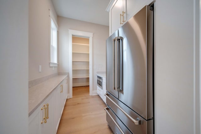 kitchen featuring white cabinets, high end fridge, and light hardwood / wood-style floors