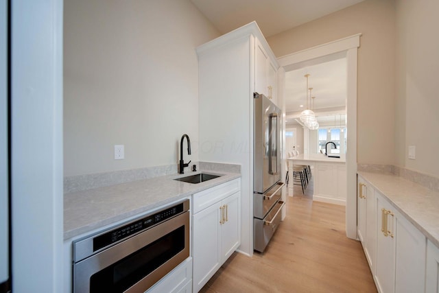 kitchen featuring white cabinetry, sink, appliances with stainless steel finishes, and light hardwood / wood-style flooring