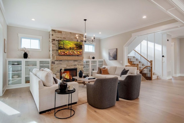 living room with a fireplace, an inviting chandelier, light wood-type flooring, and ornamental molding