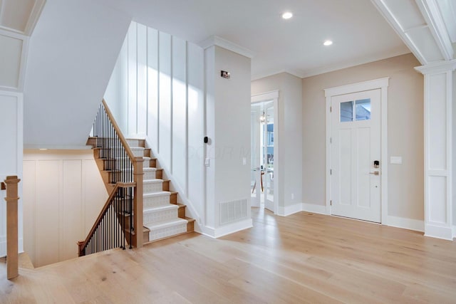 entrance foyer with ornamental molding and light hardwood / wood-style flooring