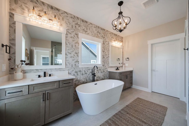 bathroom featuring tile patterned flooring, a bathtub, vanity, and a chandelier