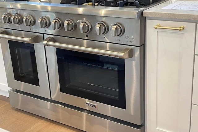 interior details with double oven range and light wood-type flooring