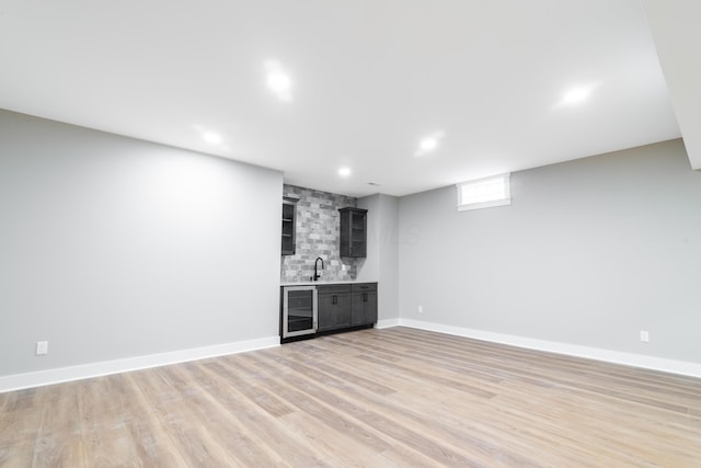 basement featuring light hardwood / wood-style floors, sink, and beverage cooler