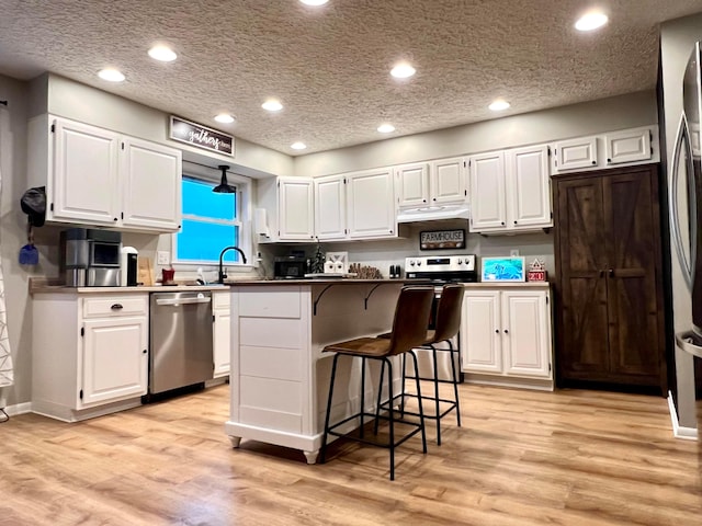 kitchen featuring white cabinets, appliances with stainless steel finishes, and light hardwood / wood-style flooring