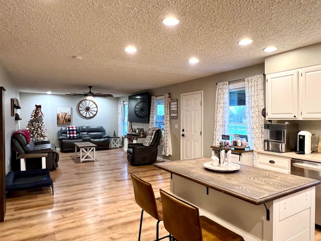 kitchen with white cabinets, ceiling fan, light wood-type flooring, and a textured ceiling