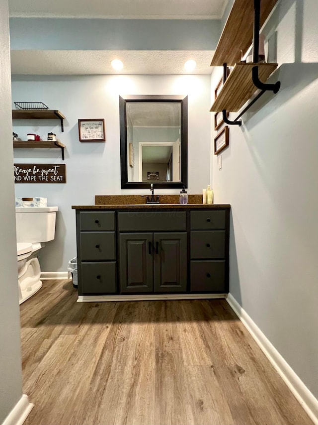 bathroom with vanity, toilet, wood-type flooring, and a textured ceiling