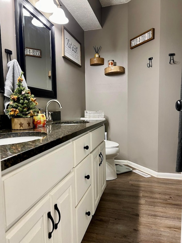 bathroom featuring hardwood / wood-style floors, vanity, a textured ceiling, and toilet