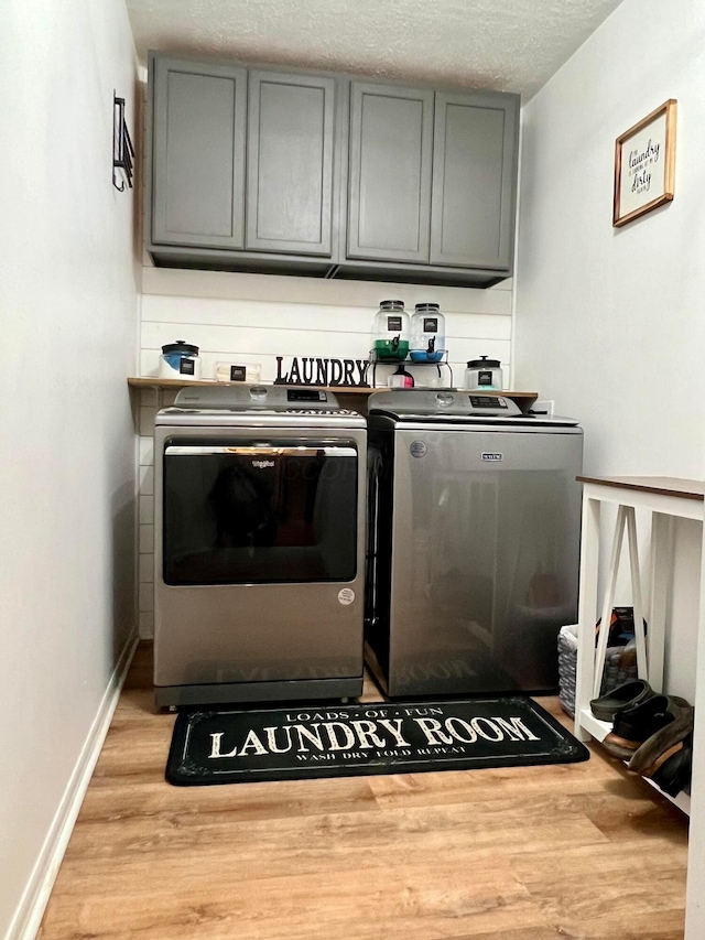 laundry area with independent washer and dryer, cabinets, light wood-type flooring, and a textured ceiling