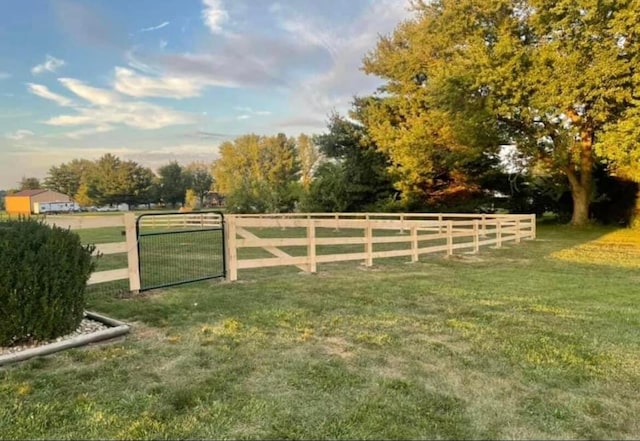 view of gate with a rural view and a lawn