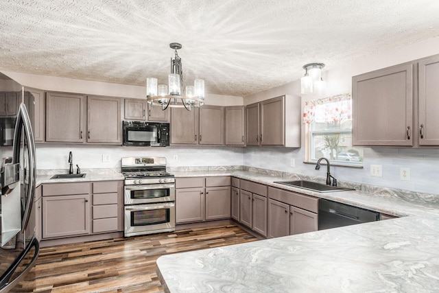 kitchen with appliances with stainless steel finishes, dark hardwood / wood-style flooring, decorative light fixtures, and sink