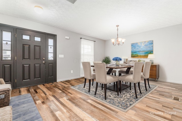 dining space with a chandelier, a textured ceiling, light hardwood / wood-style flooring, and a wealth of natural light