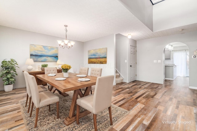 dining area featuring a textured ceiling, light hardwood / wood-style floors, and an inviting chandelier