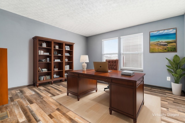 office space featuring light wood-type flooring and a textured ceiling