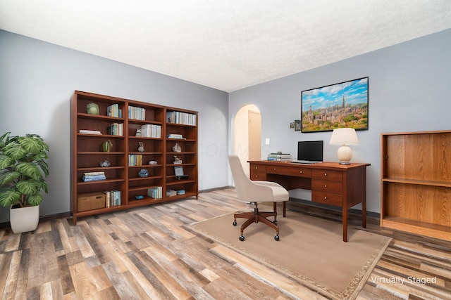 office featuring light wood-type flooring and a textured ceiling