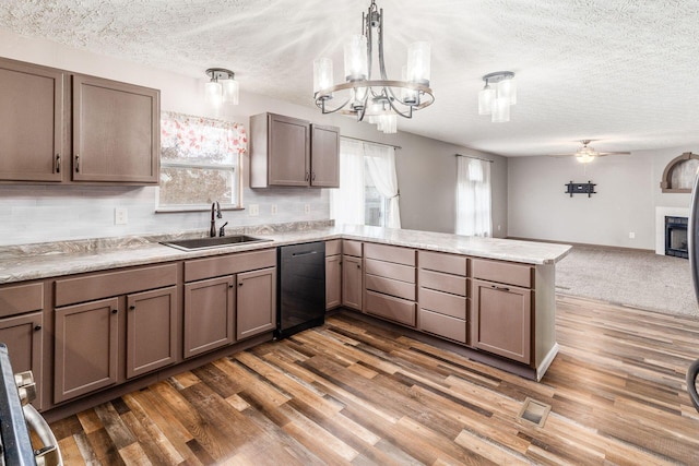 kitchen featuring dishwasher, sink, dark hardwood / wood-style flooring, kitchen peninsula, and pendant lighting