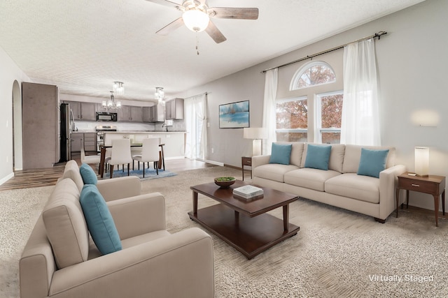 living room with light carpet, a textured ceiling, ceiling fan with notable chandelier, and sink