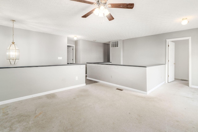 empty room featuring ceiling fan, light colored carpet, and a textured ceiling