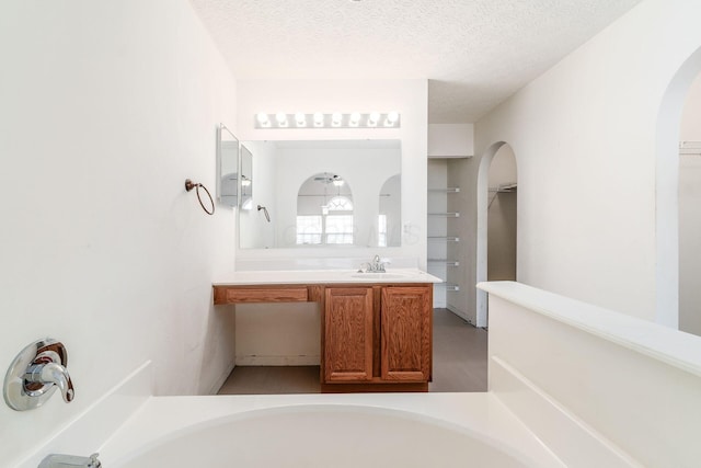 bathroom with vanity, a bathtub, and a textured ceiling