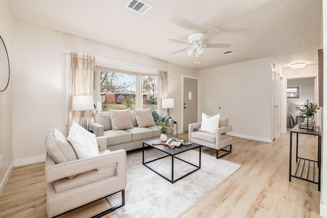 living room with a textured ceiling, light hardwood / wood-style flooring, and ceiling fan