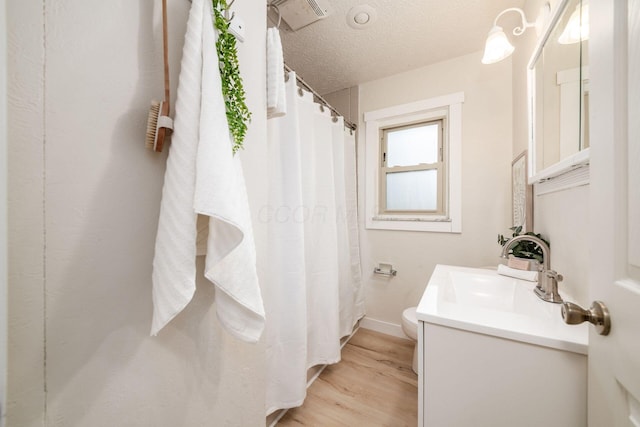 bathroom with hardwood / wood-style flooring, vanity, toilet, and a textured ceiling