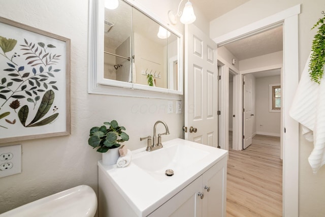 bathroom with vanity, wood-type flooring, a textured ceiling, and toilet