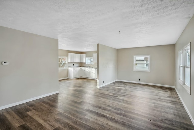 unfurnished living room featuring sink, dark hardwood / wood-style flooring, and a textured ceiling