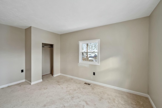 unfurnished bedroom with light carpet and a closet