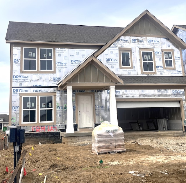 property under construction with a shingled roof, board and batten siding, and an attached garage