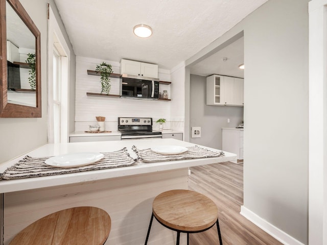 bar featuring white cabinets, appliances with stainless steel finishes, a textured ceiling, and light hardwood / wood-style floors