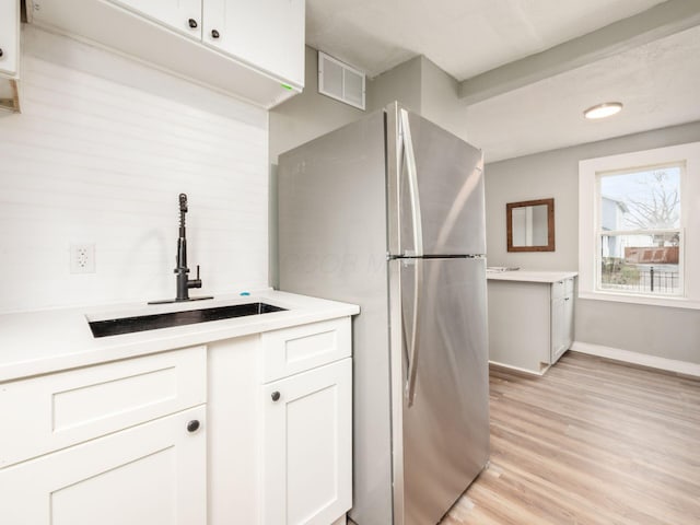 kitchen featuring stainless steel fridge, sink, white cabinets, and light hardwood / wood-style floors