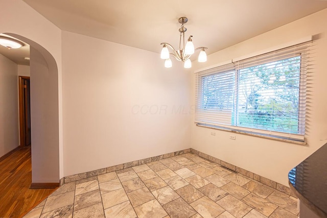 empty room featuring a notable chandelier and light hardwood / wood-style flooring