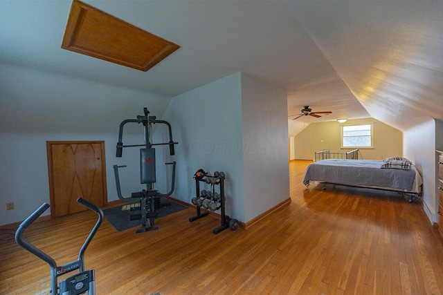 exercise room with ceiling fan, wood-type flooring, and vaulted ceiling