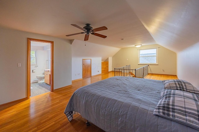 bedroom with ceiling fan, light wood-type flooring, ensuite bathroom, and lofted ceiling