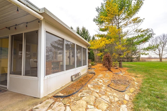 view of side of property with a sunroom and a yard