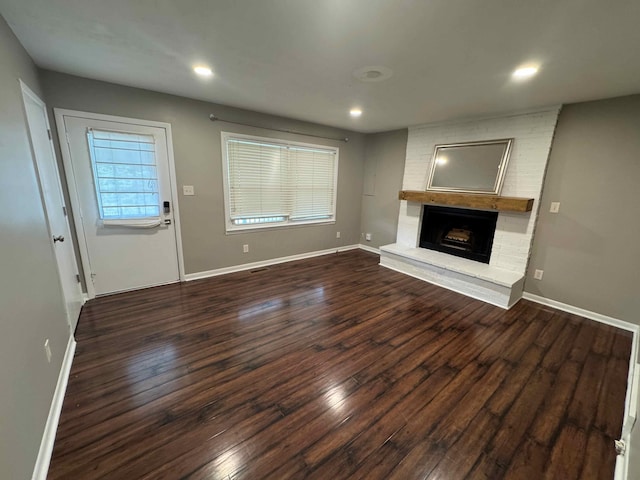 unfurnished living room featuring dark hardwood / wood-style floors and a brick fireplace