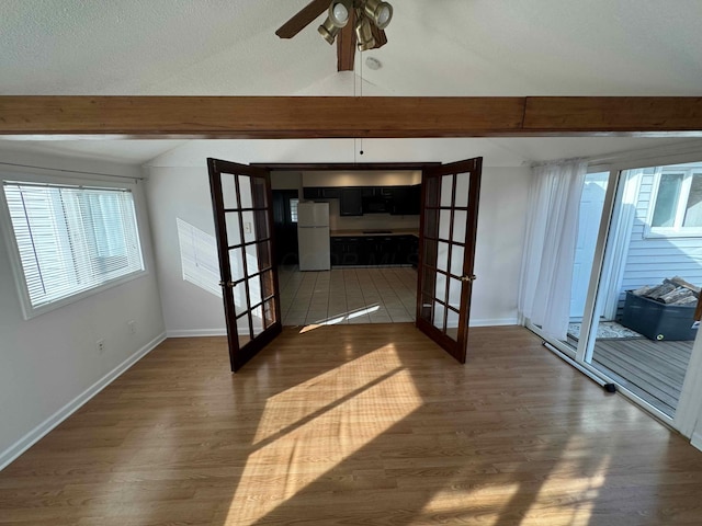 empty room with dark hardwood / wood-style flooring, ceiling fan, plenty of natural light, and french doors