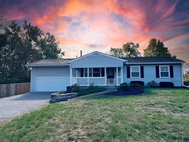 single story home featuring a porch, a garage, and a yard