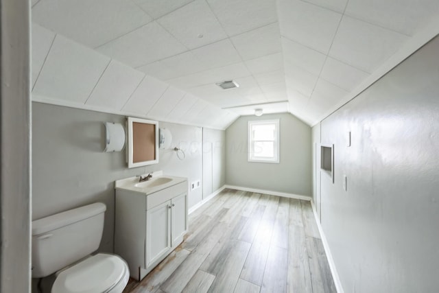 bathroom featuring vanity, hardwood / wood-style flooring, toilet, and vaulted ceiling