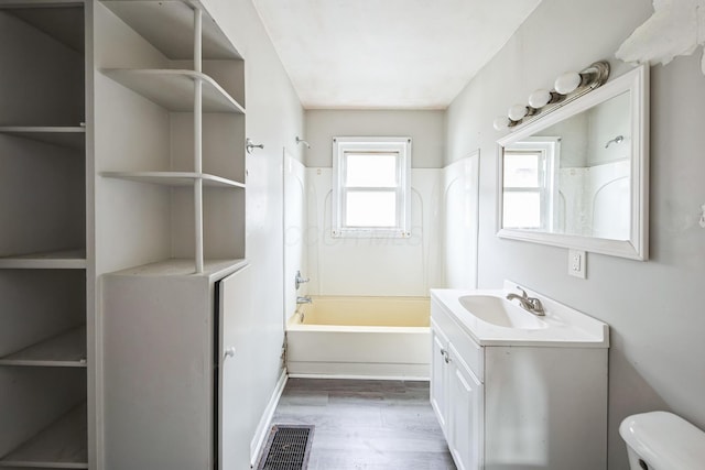 full bathroom featuring hardwood / wood-style floors, vanity,  shower combination, and toilet