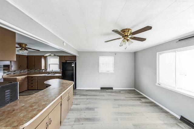 kitchen featuring black refrigerator, light hardwood / wood-style floors, plenty of natural light, and sink