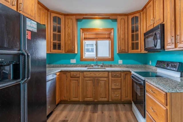 kitchen with light stone countertops, sink, light hardwood / wood-style floors, and black appliances