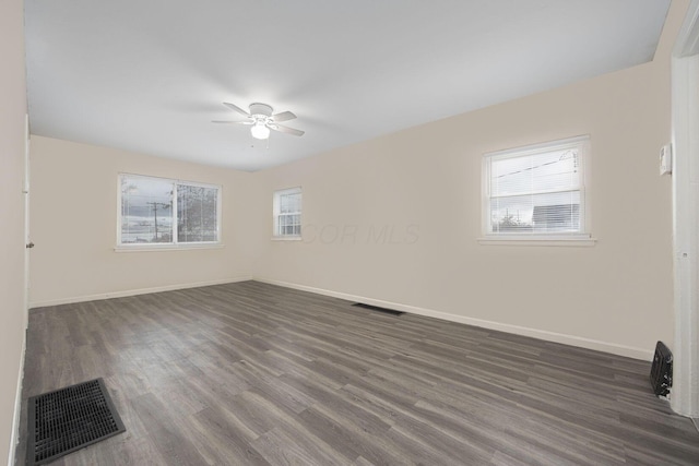 spare room with ceiling fan, plenty of natural light, and dark wood-type flooring