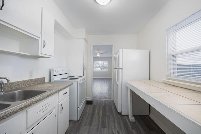 kitchen with white appliances, dark wood-type flooring, sink, tile counters, and white cabinetry