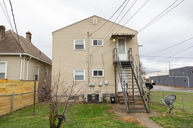 rear view of property with central AC unit and a lawn