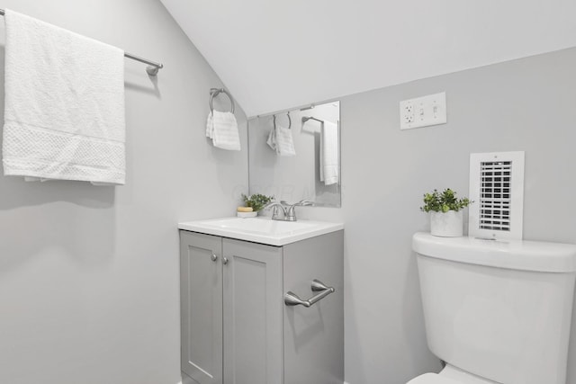 bathroom with vanity, toilet, and vaulted ceiling